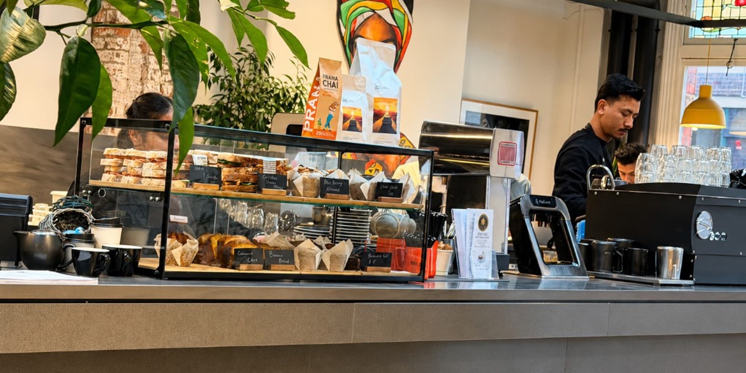 Nest Cafe counter with pastry display and barista preparing coffee